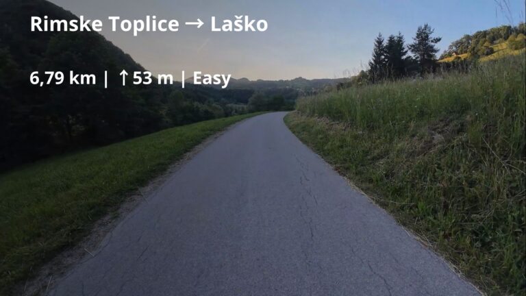 Cycling route from Rimske Toplice to Laško in Slovenia, following a quiet asphalt road through the Savinja Valley with green hills in the background.